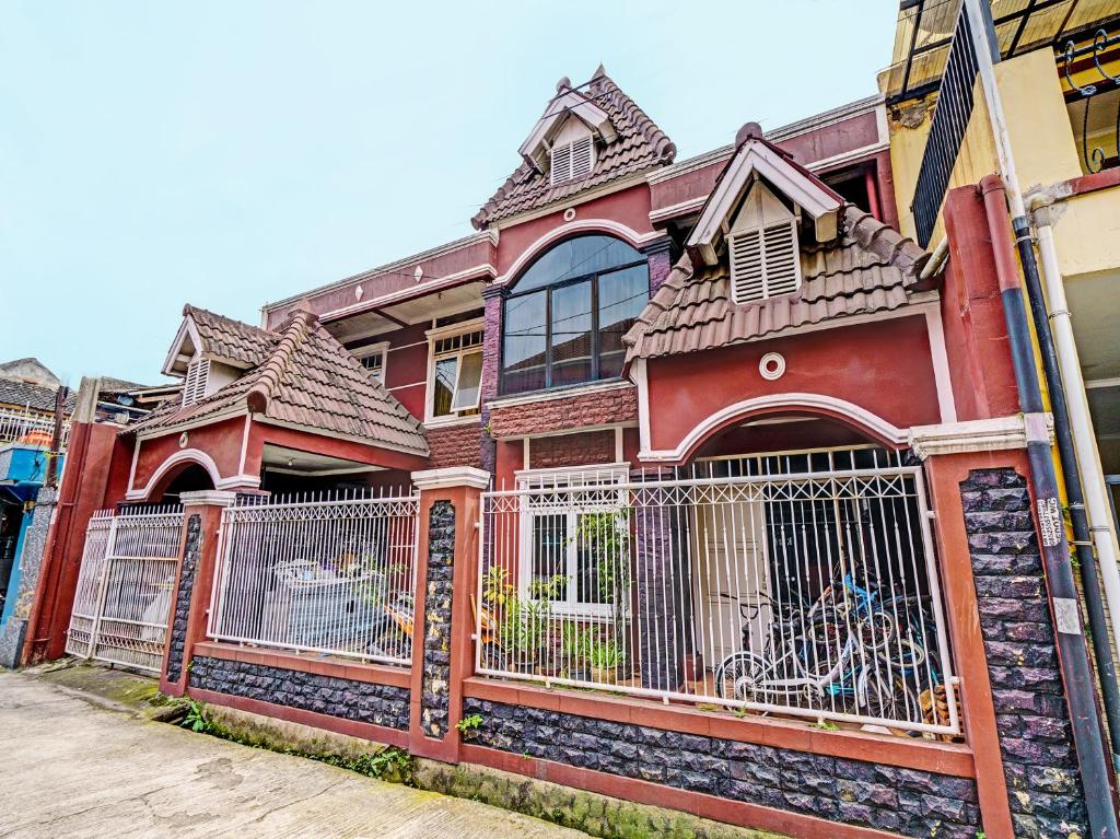 een rood huis met een hek ervoor bij OYO Life 92546 Kost Merah Bojongsoang Syariah in Bandung