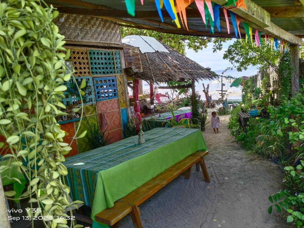 a wooden bench sitting under a building with a little girl at Shirley's Cottage - Pamilacan Island in Baclayon