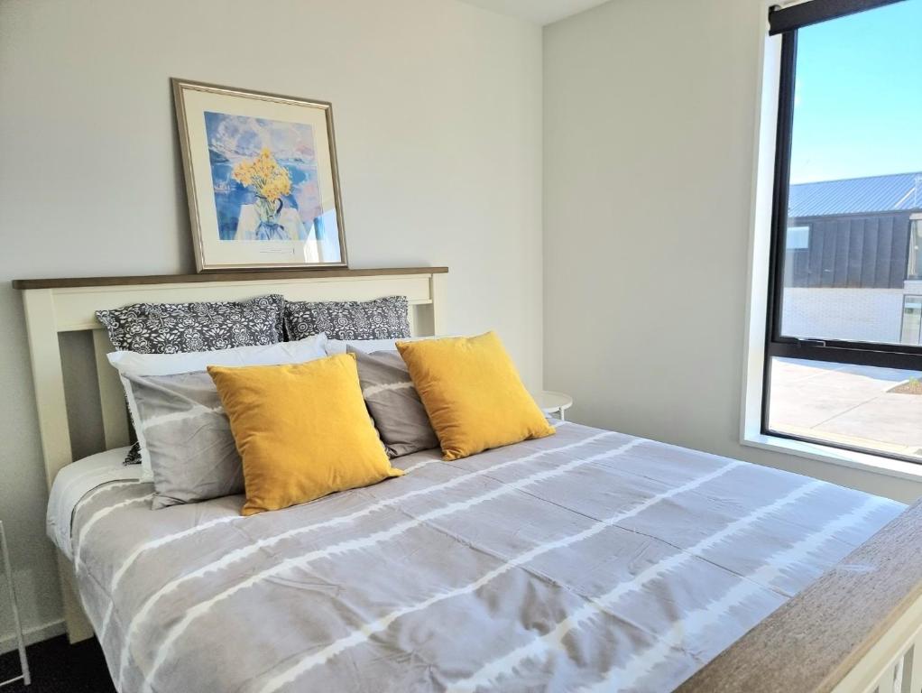 a bedroom with a bed with yellow pillows and a window at Addington townhouse with carpark 8mins walk to Hagley park south in Christchurch