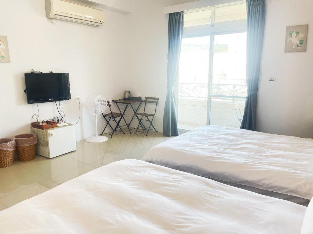 um quarto branco com uma cama e uma televisão em 薇琪小屋 em Hualien City