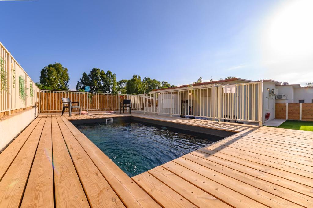 uma piscina num deque de madeira com uma casa em דירת נופש מרחבים Merhavim Villa em Shadmot Devora