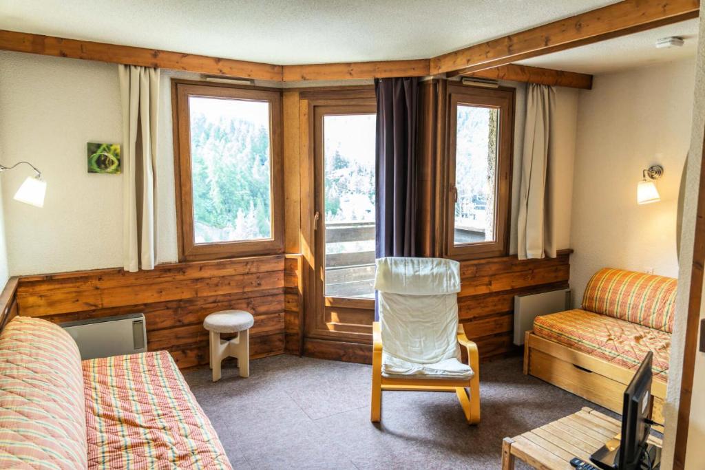 Cette chambre comprend un lit, une chaise et des fenêtres. dans l'établissement Résidence Le Belvedere - Studio coin montagne au coeur des Orres 1650 MAE-6324, aux Orres