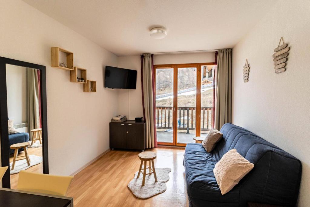 un salon avec un canapé bleu et un balcon dans l'établissement Résidence Les Terrasses Du Soleil D'or - Agréable appartement au pied des pistes MAE-6394, aux Orres