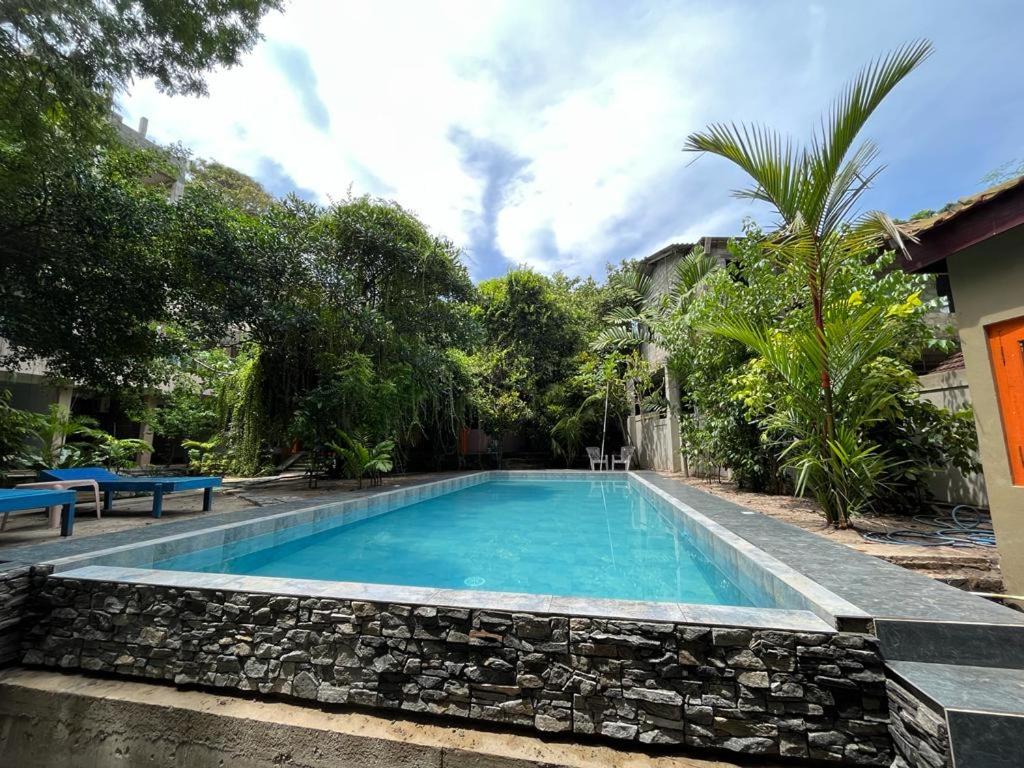 a swimming pool with a stone wall around it at Monkey villa in Hikkaduwa