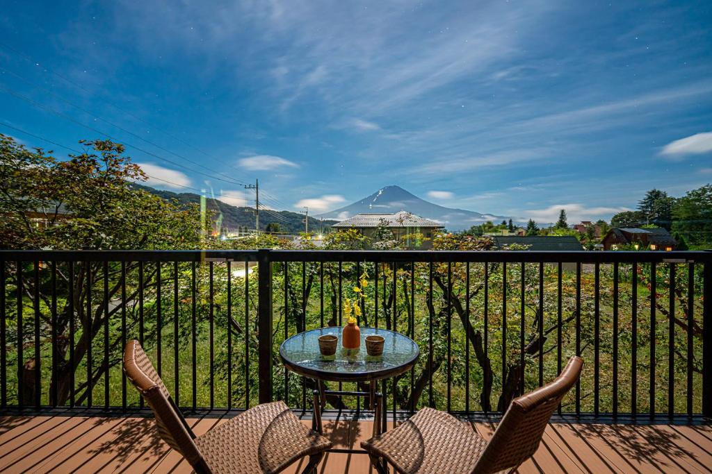 uma mesa e cadeiras numa varanda com vista para uma montanha em View of Mt Fuji Free transportation Bicycle Rental ok 富士山眺望 em Fujikawaguchiko