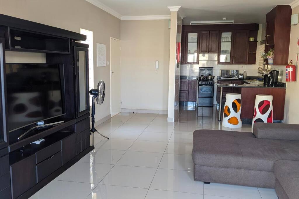 a living room with a couch and a kitchen at Holiday Haven in Gaborone