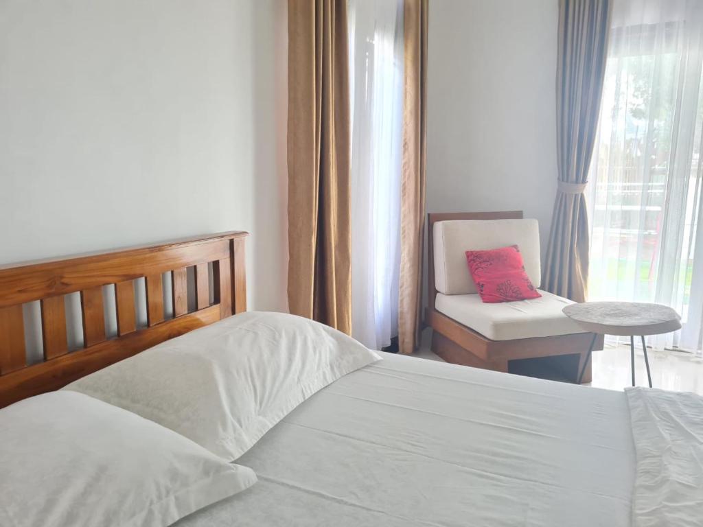 a bedroom with a bed and a chair and a window at Inang Amang Homestay in Labuan Bajo