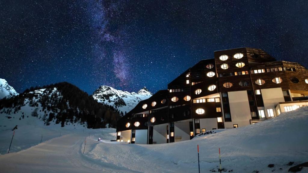 un edificio nella neve di notte con le stelle di Aparthotel Maso Corto a Maso Corto