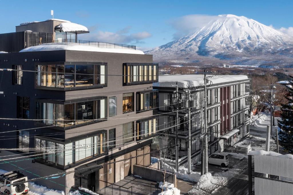 een gebouw met een met sneeuw bedekte berg op de achtergrond bij Dharma Niseko(ダーマニセコ) in Kutchan