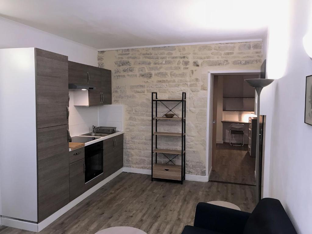 a kitchen with wooden cabinets and a stove top oven at Appartement climatisé Barjac centre ville in Barjac