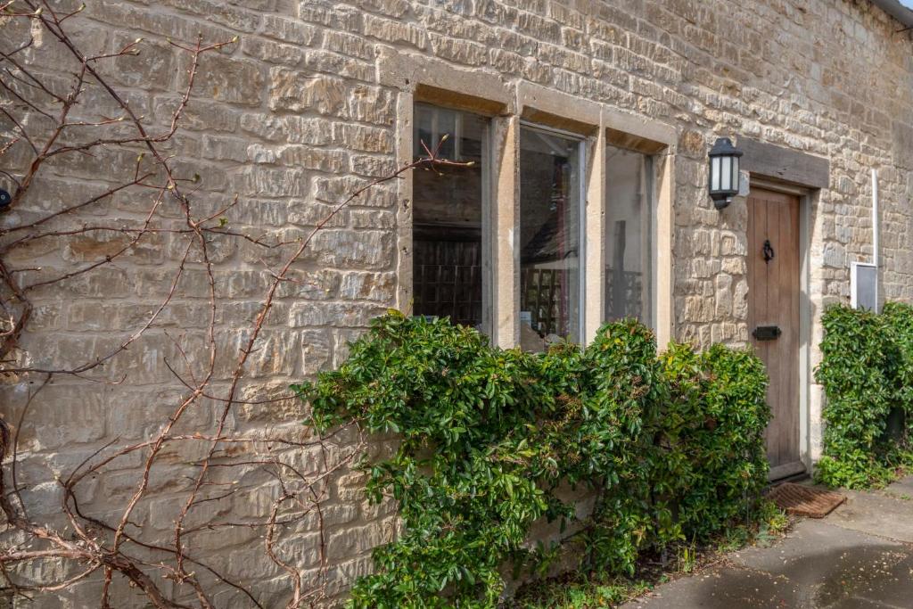 un edificio de ladrillo con puerta y ventana en Traditional Cotswold Stone Peaceful Cottage with stunning views, en Stroud