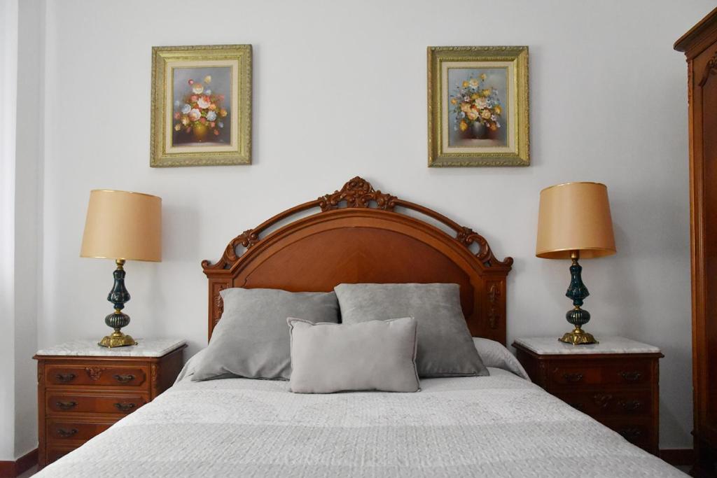 een slaapkamer met een bed met twee lampen en twee foto's aan de muur bij Apartamento Santa cruz in Sevilla