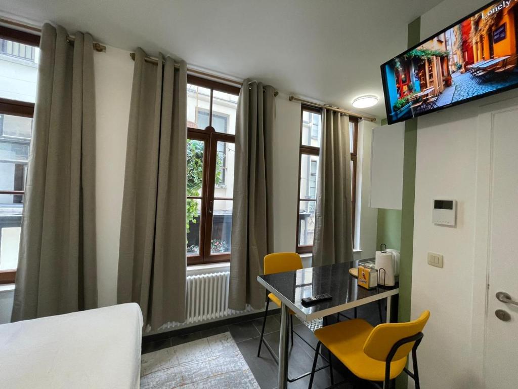 Zimmer mit einem Schreibtisch, Stühlen und Fenstern in der Unterkunft Apartament in Brüssel