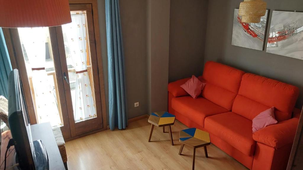 sala de estar con sofá naranja y ventana en Apartamento en Villanua La Espata, en Villanúa