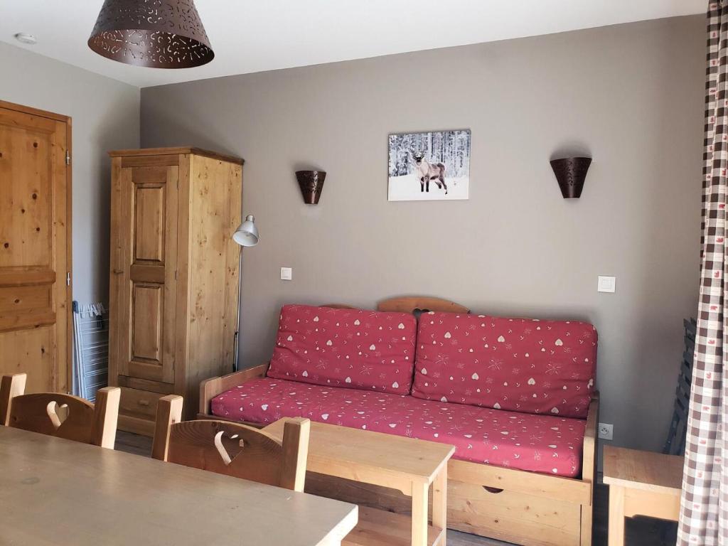 un soggiorno con divano rosso e tavolo di Les Chalets Des Rennes - 2 Pièces pour 4 Personnes 534 a Vars