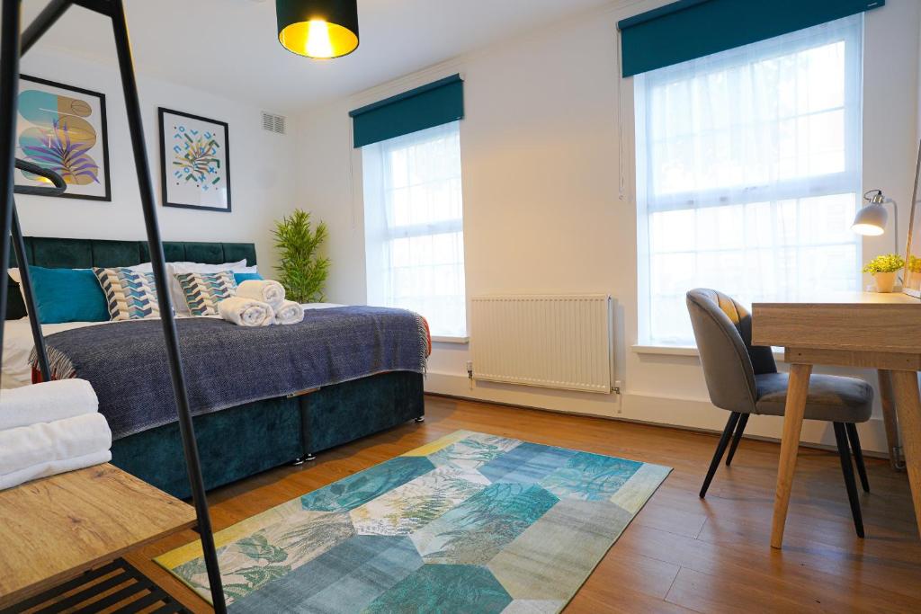 a bedroom with a bed and a table and a desk at Enfield North London 3BR Apartment in London