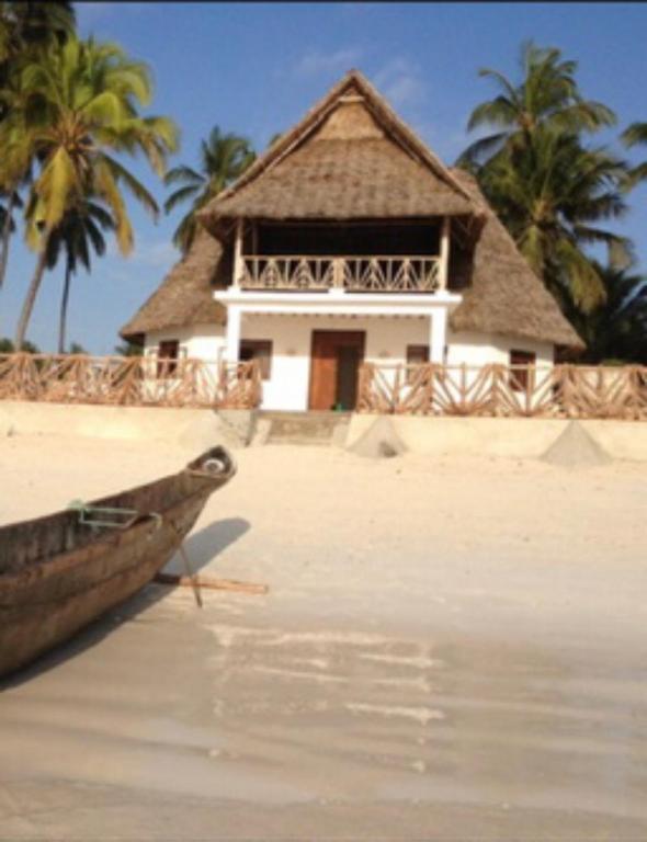 a building on a beach with a boat in the water at The Loft Zanzibar Kikadini Beach in Jambiani