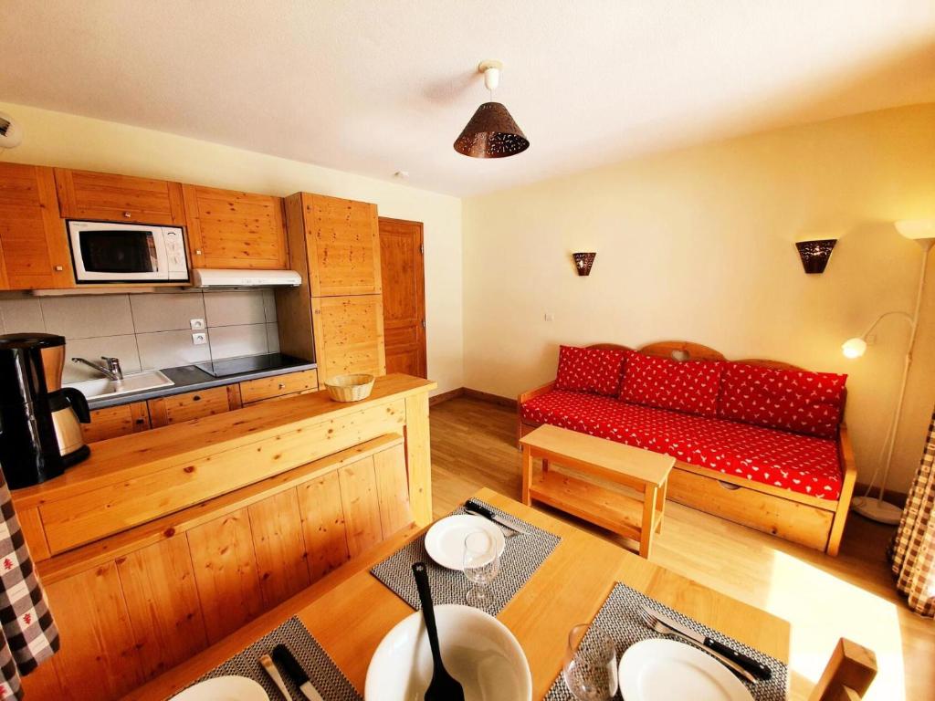 un salon avec un canapé rouge dans une cuisine dans l'établissement Les Chalets Des Rennes - Appartement 2 pièces - Les Chalets Des Rennes MAE-9764, à Vars