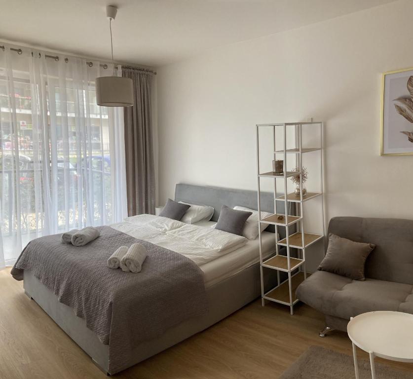 biała sypialnia z łóżkiem i krzesłem w obiekcie Apartament studio Perła 2 w mieście Lublin