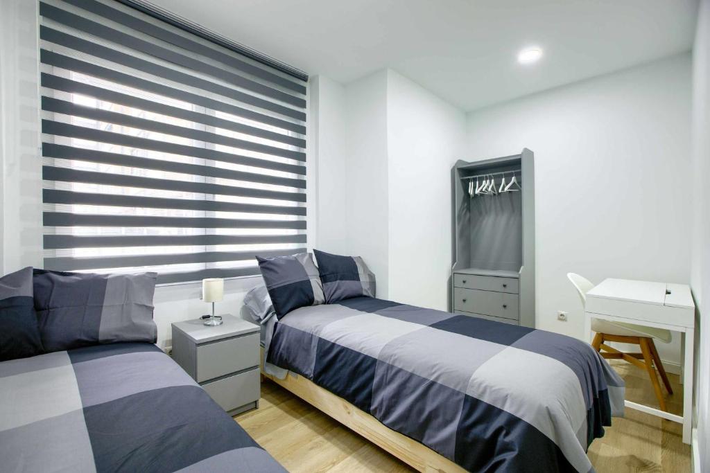 a bedroom with two beds and a tv in it at Casa de Huéspedes 12 Octubre Rooms in Madrid