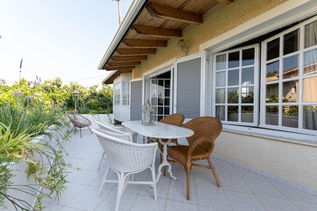 een patio met een witte tafel en stoelen bij Serene Seaside Bliss - Lush & Secluded Garden Oasis in Kalamata