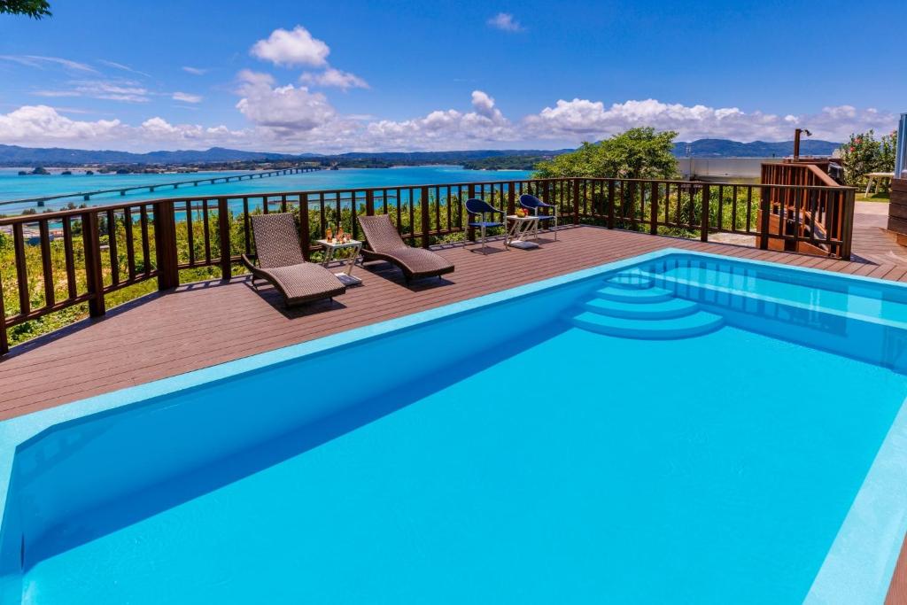 una piscina con sedie e un ponte con vista sull'acqua di KOURI Ocean Moon Cottage - Vacation STAY 05891v a Kouri