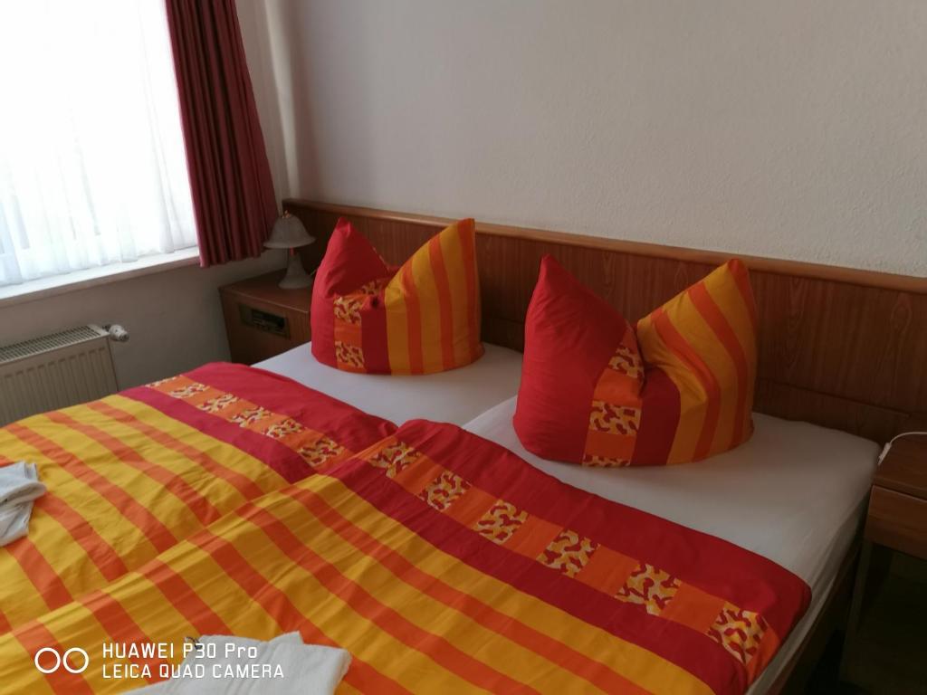- une chambre avec un lit doté d'oreillers rouges et jaunes dans l'établissement Pension Am Stadion, à Kölleda