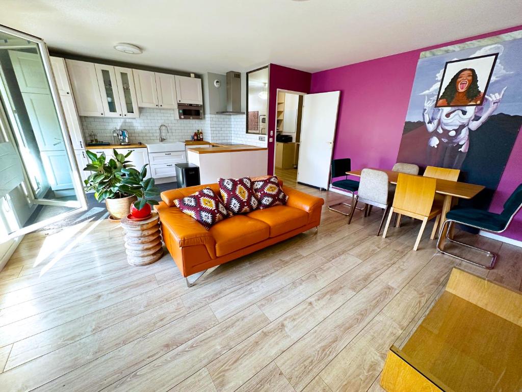 a living room with an orange couch and a kitchen at uta house la plaine in Saint-Denis