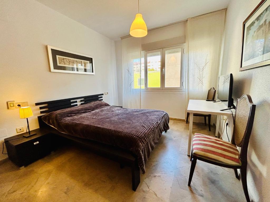 a bedroom with a bed and a desk and a chair at Guest house Teatinos in Málaga