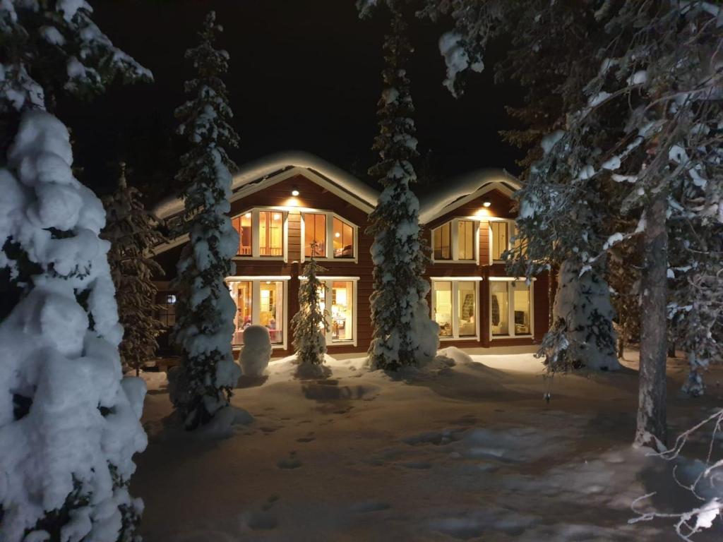 une maison recouverte de neige la nuit avec des lumières dans l'établissement Jaloilevi - Kätkänrinne, à Kittilä