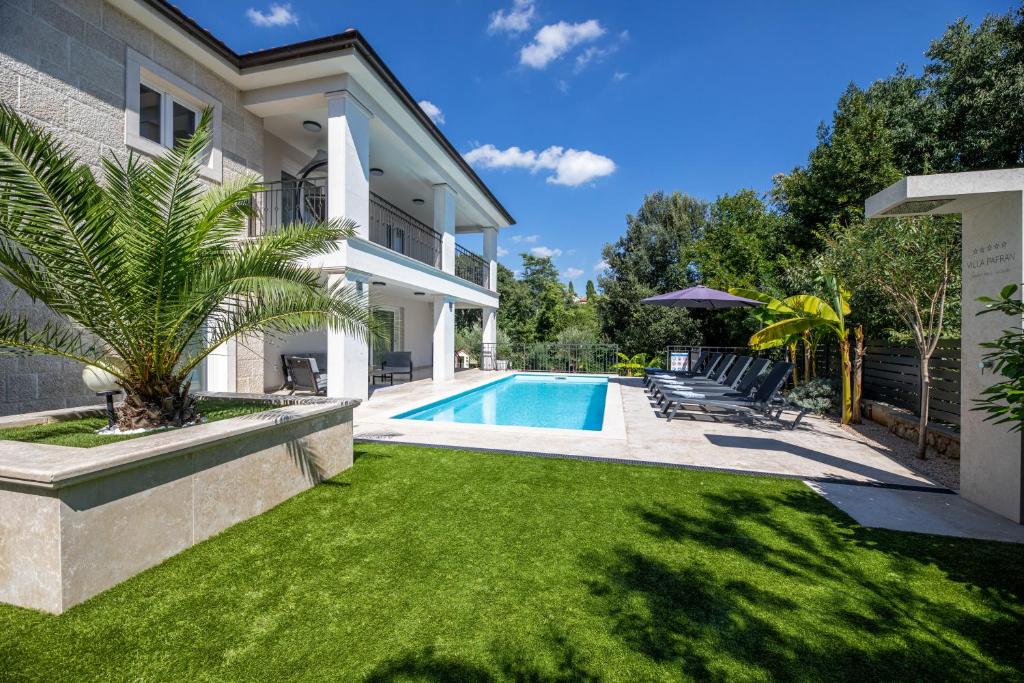 a house with a swimming pool and a yard at Villa Pafran with heated pool Krk in Krk