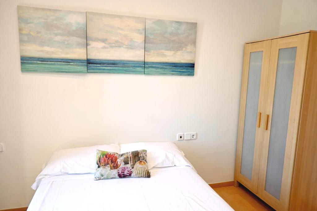 Un dormitorio con una cama blanca con un cuadro en la pared. en Homenfun Barcelona Plaza España, en Barcelona