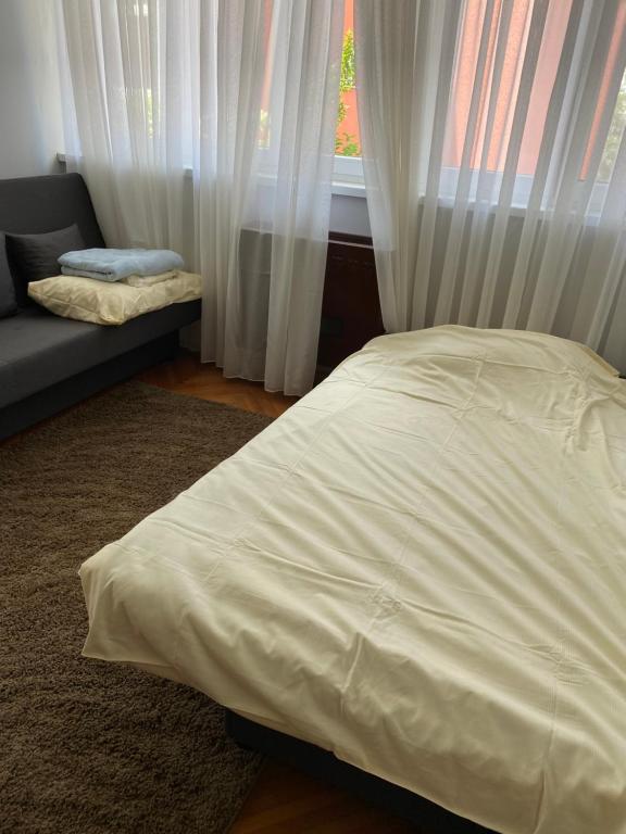 a bedroom with a bed and a window with curtains at Apartman NB in Sarajevo