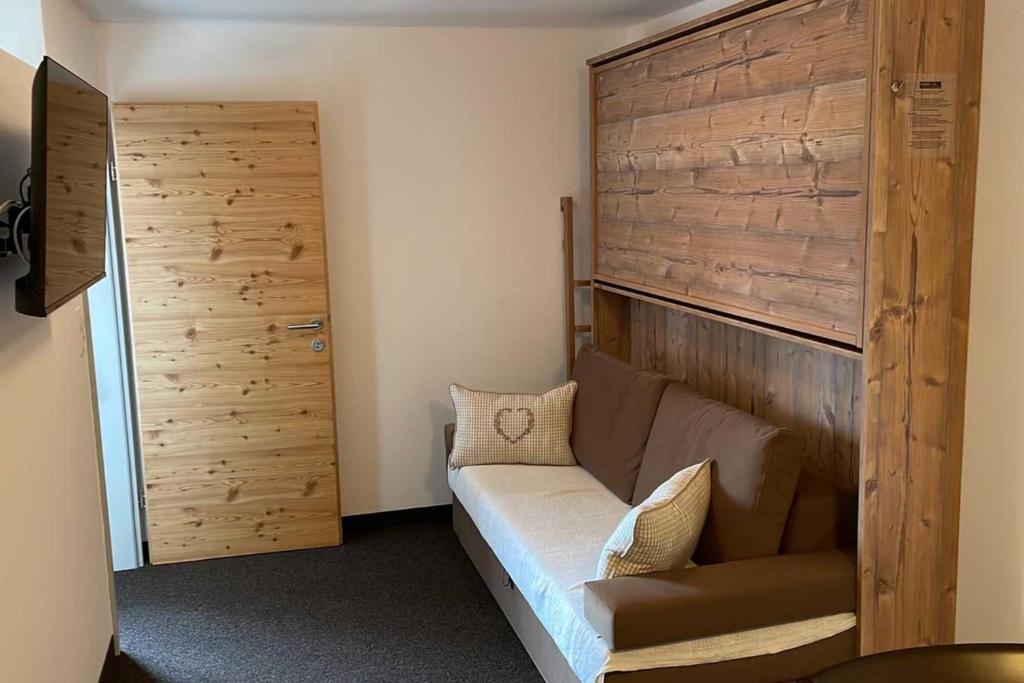 Habitación con sofá y pared de madera. en Wohnung Kreuzjoch 142- Naviser Huette, en Navis