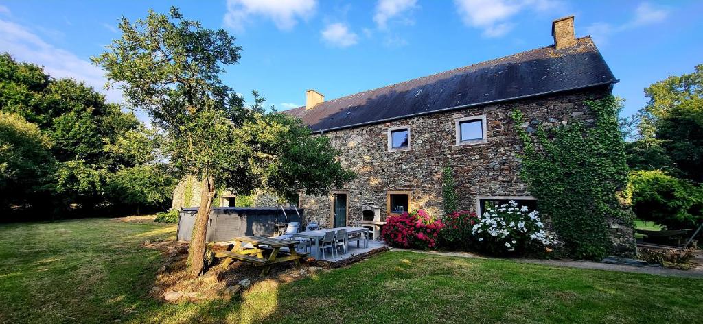 an old stone house with a picnic table in the yard at Luxury Farmhouse Brittany in Plénée-Jugon