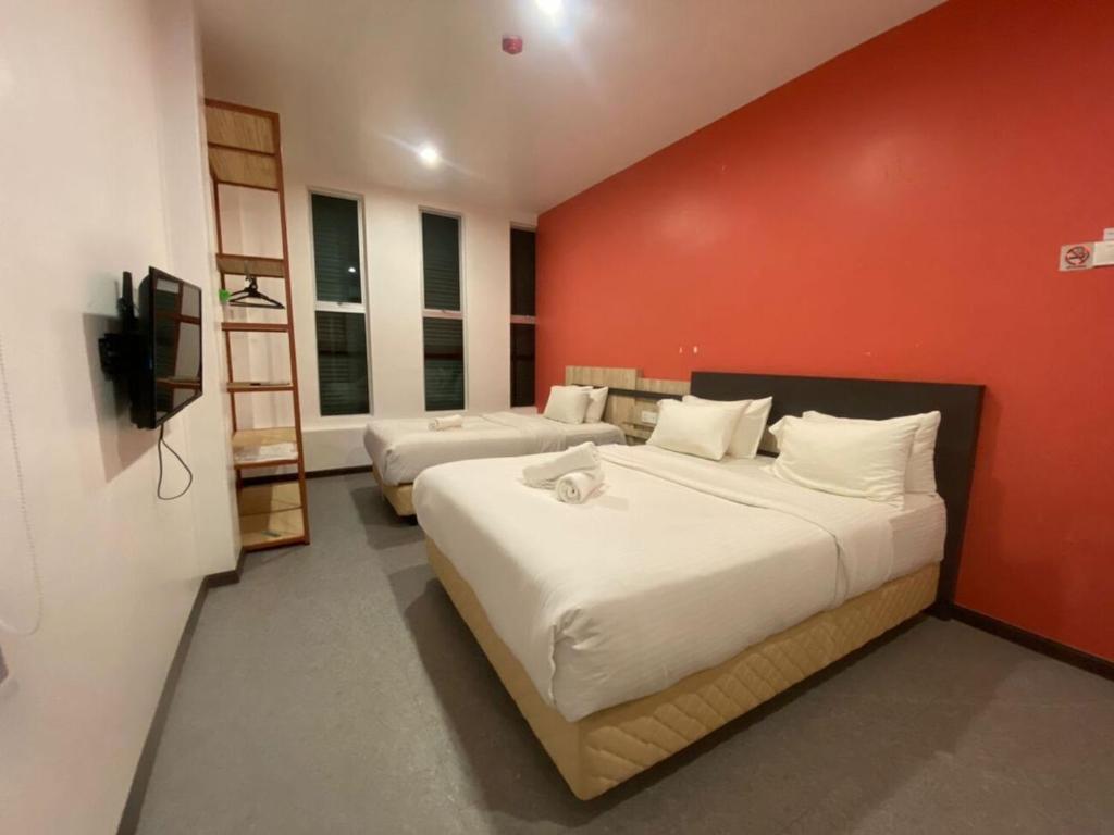 a bedroom with a large bed and a red wall at TT Dorf Hotel Taiping in Taiping