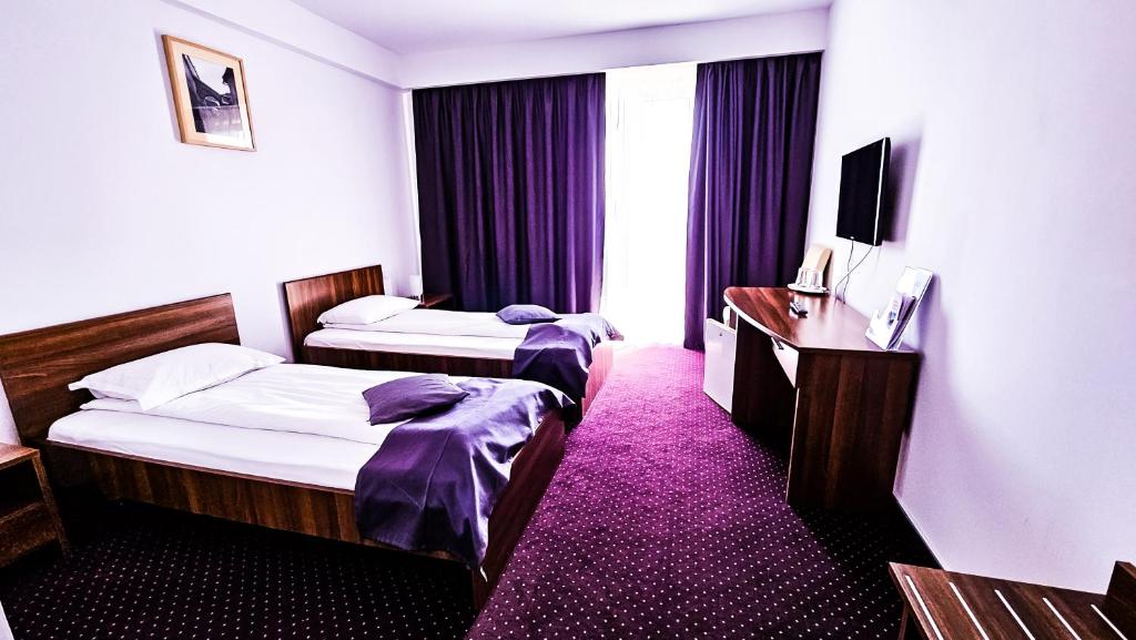 a hotel room with two beds and a desk at Hotel Eden in Sibiu