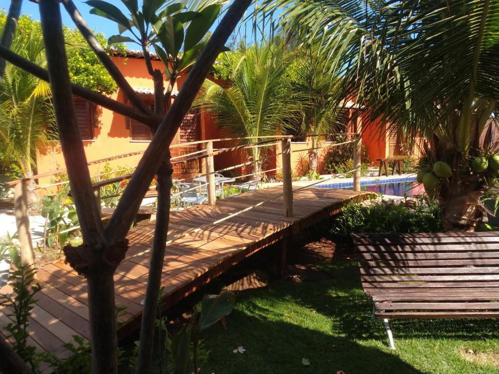 a wooden walkway leading to a pool with palm trees at Chalés Farol Village in Fortim