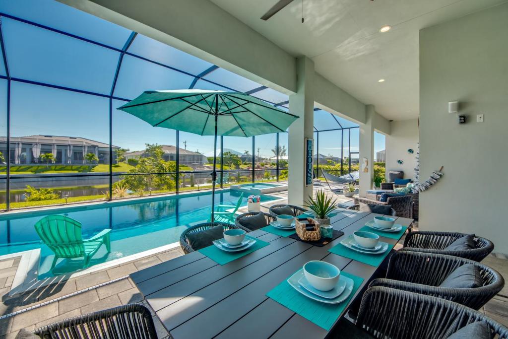 uma sala de jantar com mesa e cadeiras e uma piscina em Villa Mangifera with Salt Water Pool & Spa, EV-Loading em Cape Coral