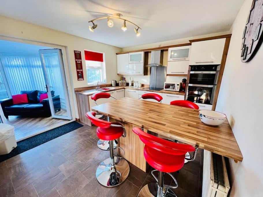 een keuken met rode krukken aan een houten aanrecht bij Home from Home - short walk from Central Portrush in Portrush