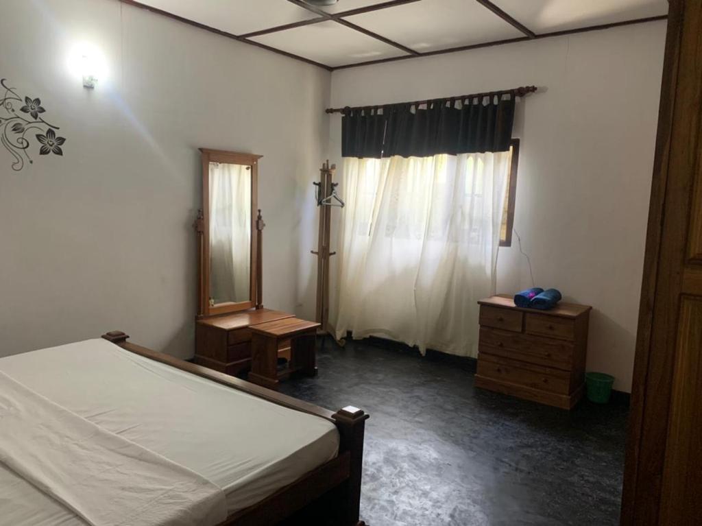 1 dormitorio con cama, tocador y espejo en LEO nature home, en Dodanduwa