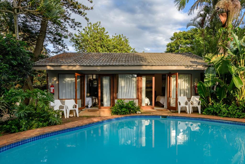 a house with a swimming pool in front of a house at Hlulala Guest House in Hluhluwe