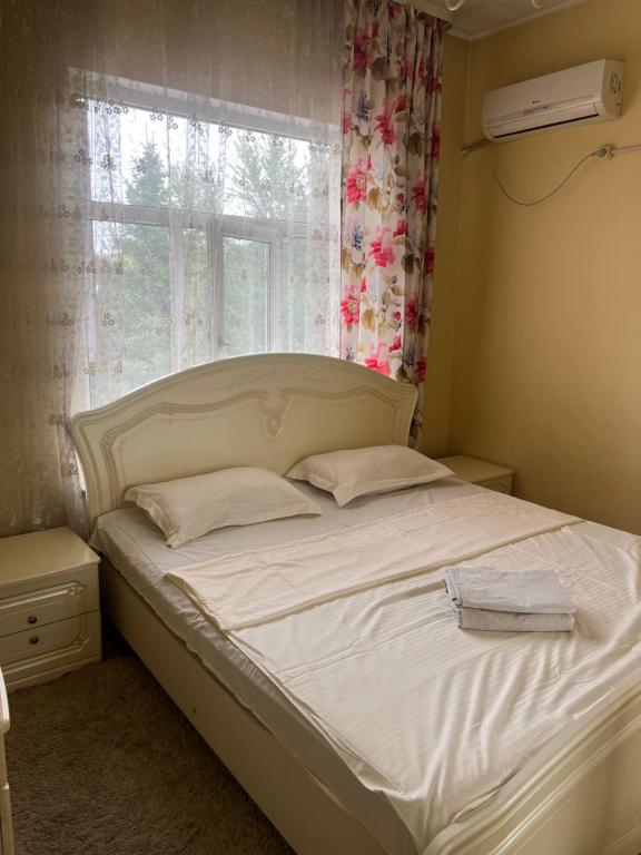 a white bed in a bedroom with a window at Eurasia hotel in Almaty