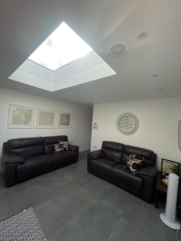 a living room with two leather couches and a skylight at Skylight Deluxe Apartment with free parking, close to Windsor, Legoland and Heathrow in Farnham Royal