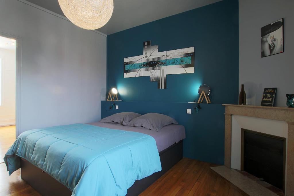 een blauwe slaapkamer met een bed en een open haard bij L'Iliade - Chambres d'hôtes - B&B à Bouzy in Bouzy