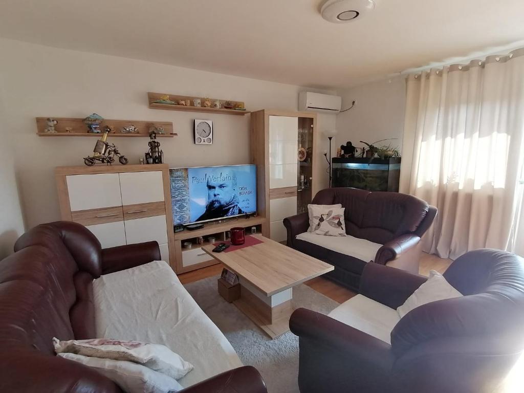 uma sala de estar com 2 sofás e uma televisão de ecrã plano em Airport Apartment em Surčin