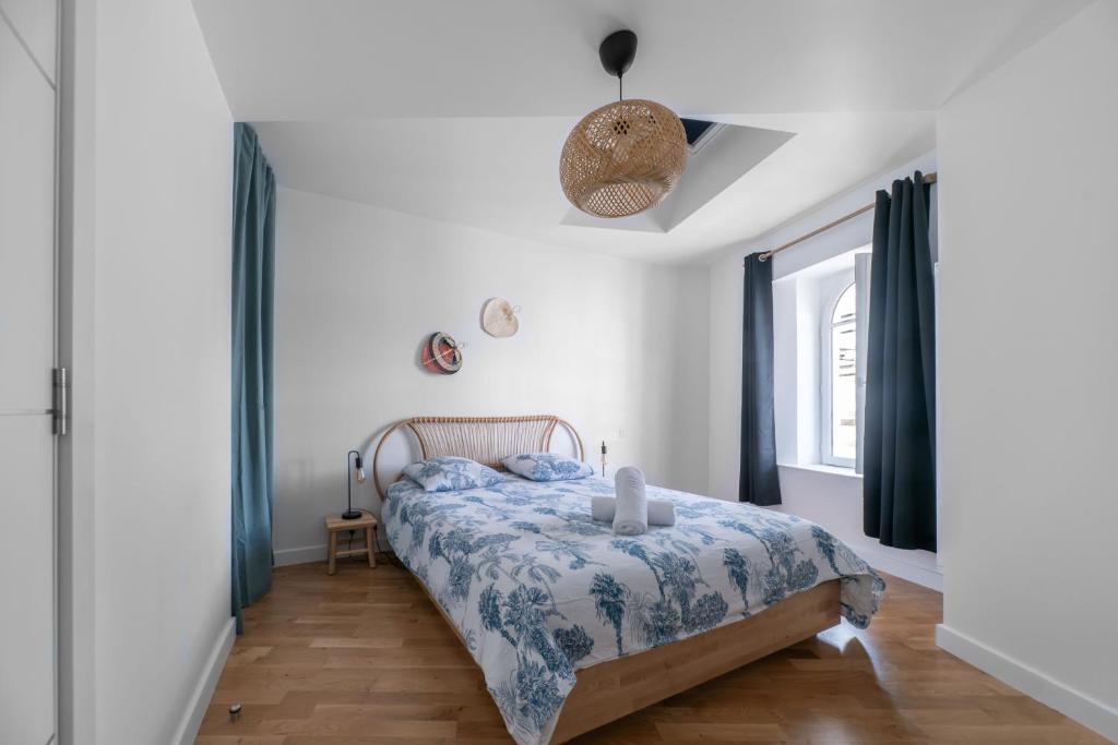 Le Wilson - Appartement design - Hyper centre في فيشي: غرفة نوم بسرير لحاف ازرق وبيض