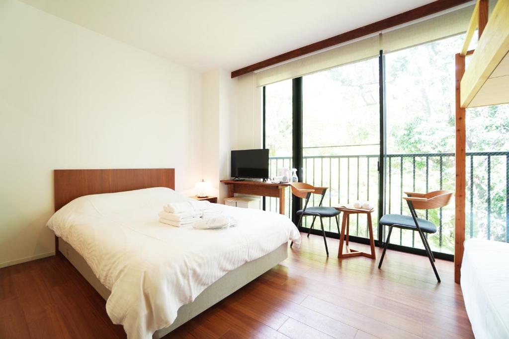 Bird Hostel في Shimmachidōri: غرفة نوم بسرير ومكتب وشرفة