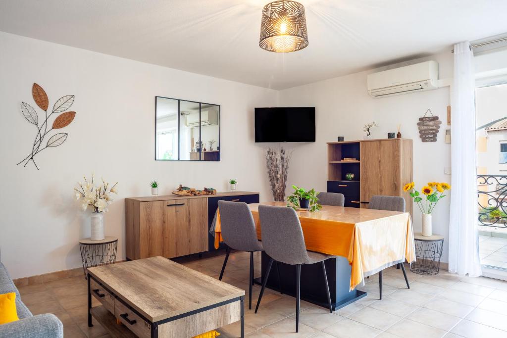 un soggiorno con tavolo, sedie e TV di Appartement T2 entièrement rénové a Saint-Cyr-sur-Mer