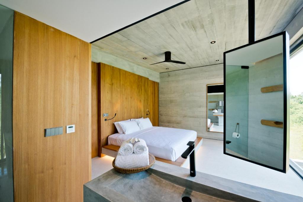 um quarto com uma cama e uma parede de vidro em Cape Pakarang Wow Wild Wellness Escapes em Khao Lak
